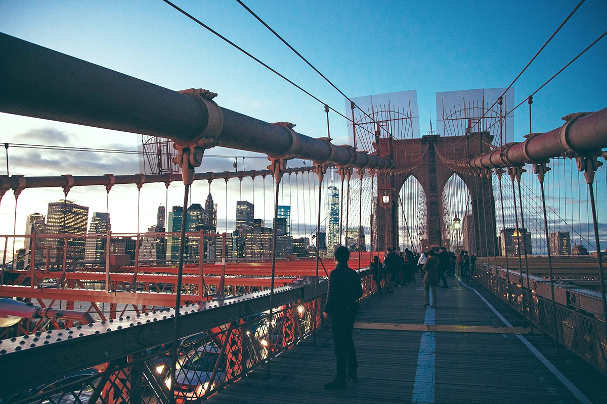 Man looks at cityscape on Brooklyn bridge